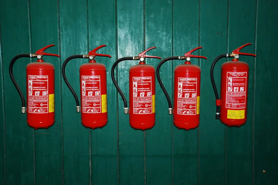 Cuatro extintores alineados contra una pared verde